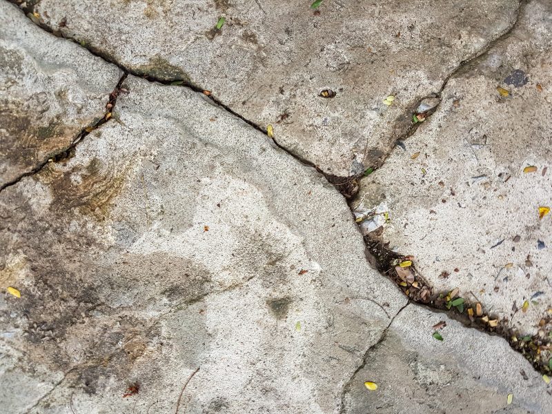Cracked and uneven concrete surface showing damage that needs fixing sinking concrete to restore level ground.